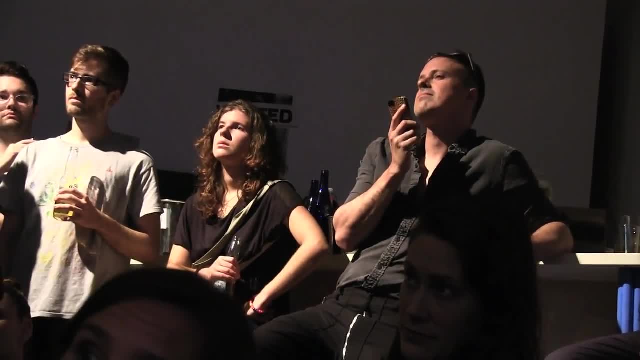 Two performeres surrounded by audience members in an intimate space.