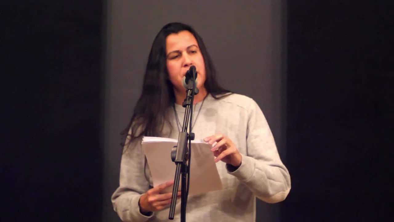 A person reads from a printed text on a microphone