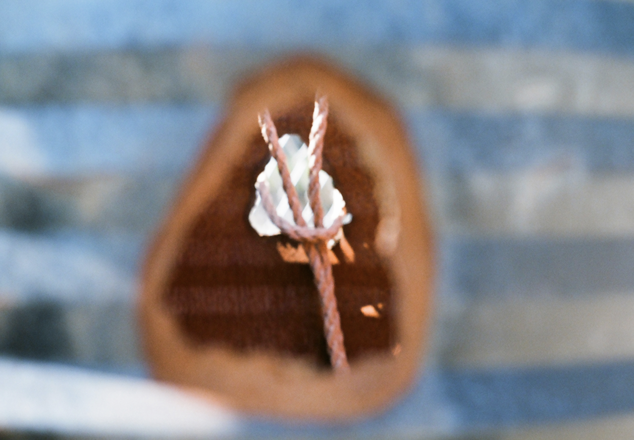 A photograph with a striped blue and white blurry background. In the center of the image, outlined in a blurry orange circle, is a clear image of a rope tied into a knot, holding a white object