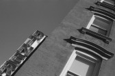 A skewed black-and-white image looking up at the façade of a building and the sky. An LED sign spelling 
