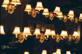 A close-up phot of a group of of small, lit lamps hanging on a glass wall in an ornate building.
