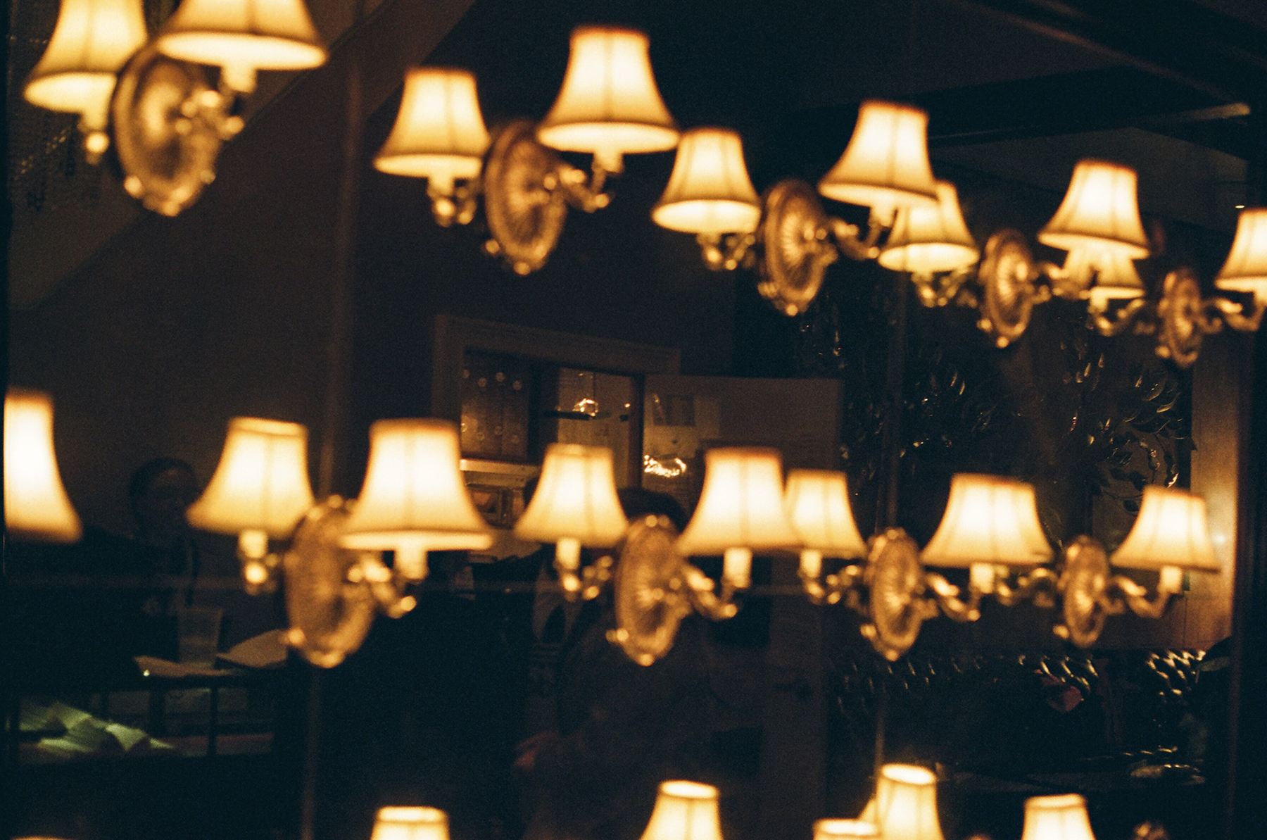 A close-up phot of a group of of small, lit lamps hanging on a glass wall in an ornate building.