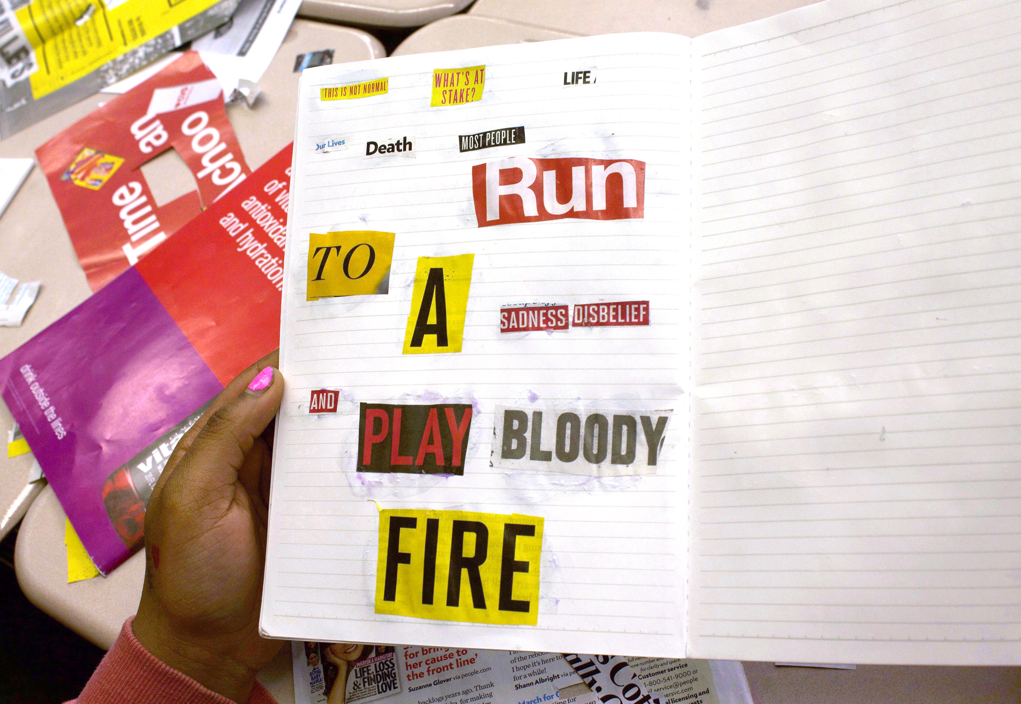 A hand holds up a lined notebook with a poem collaged from newspaper cutouts which says, 