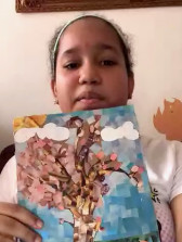 A student holds up artwork depicting her family tree.