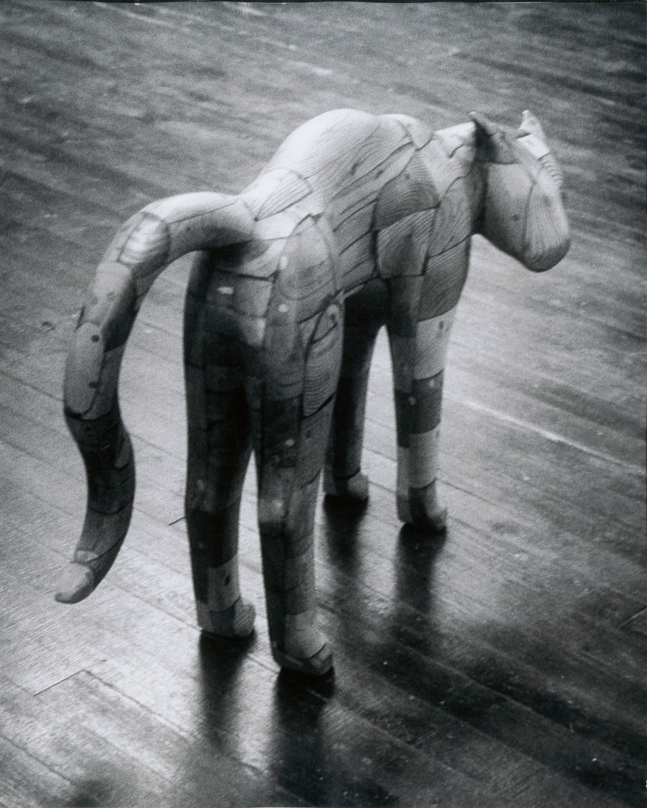 A black and white photograph of a wooden sculpture of a cat with an arched back.