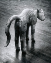 A black and white photograph of a wooden sculpture of a cat with an arched back.