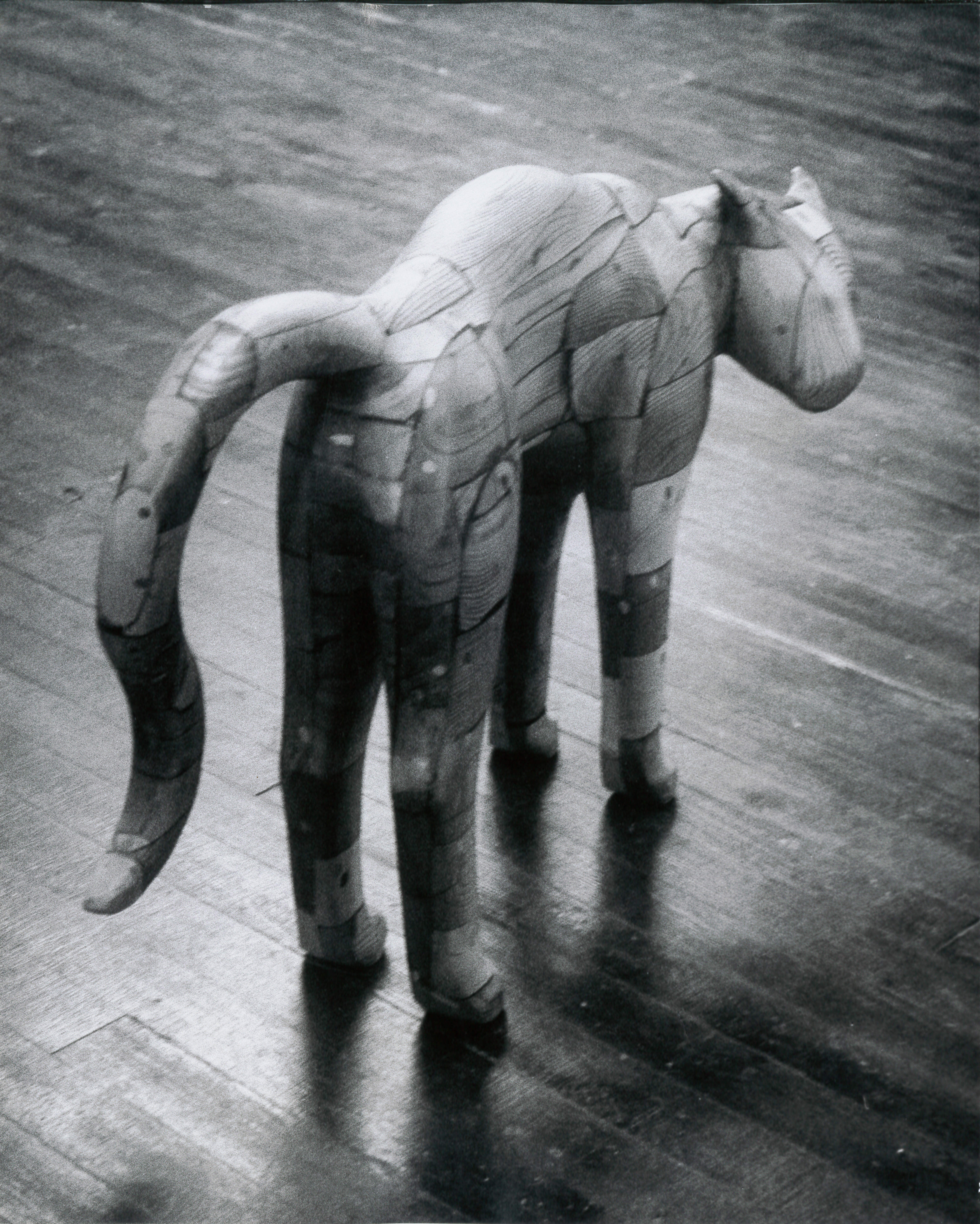A black and white photograph of a wooden sculpture of a cat with an arched back.
