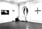 Photographic and sculptural works appear in a white-walled gallery space.