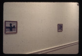 Two images hang on a white wall, far apart.