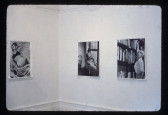 Three black and white photographs hang on white walls in the corner of a room. The photos depict a woman in various positions: laying down, reaching up to a bookshelf, and sitting on a ledge gazing out a window.