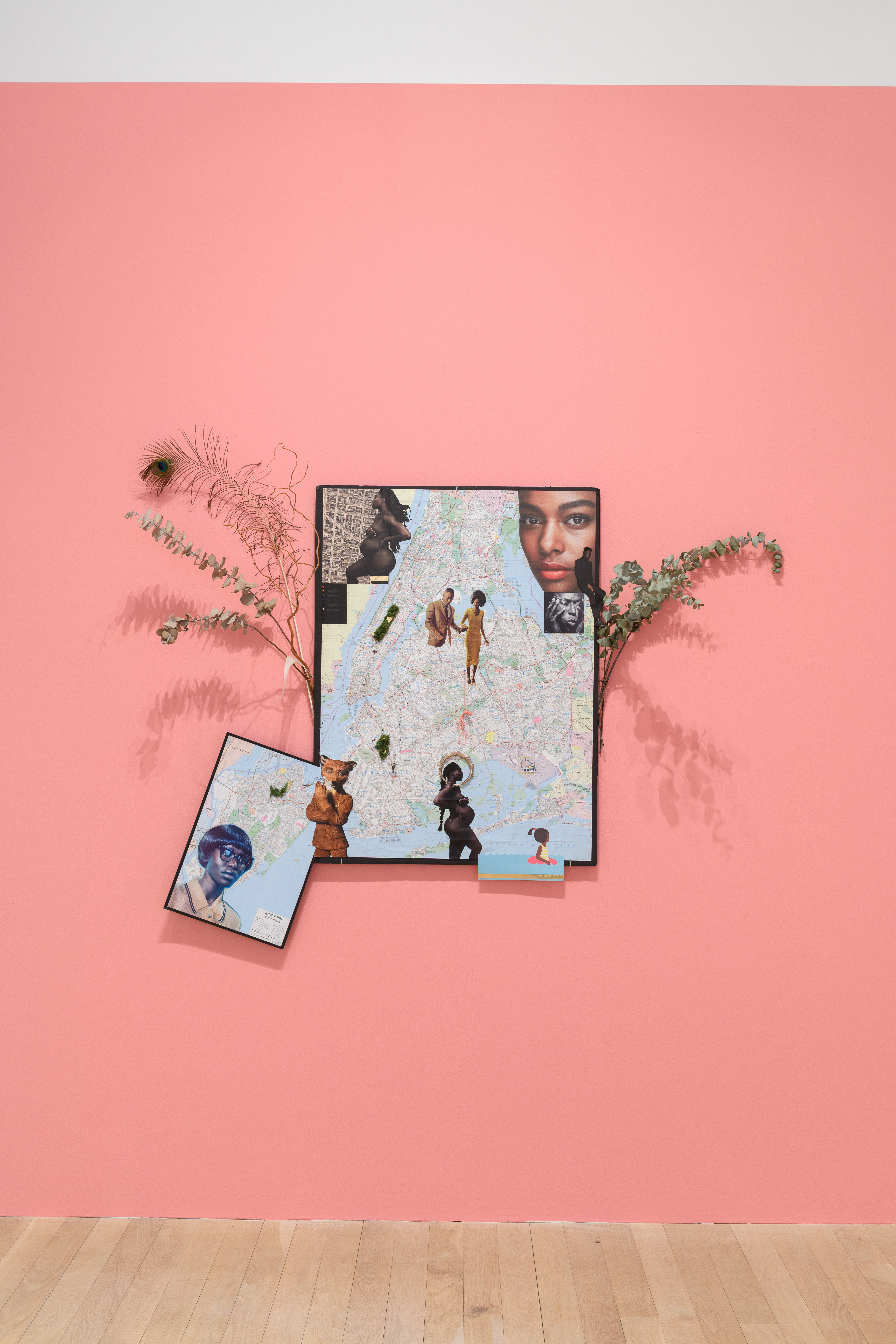 A collage of eucalyptus sprigs, other plants, and human figures attached to a framed map.