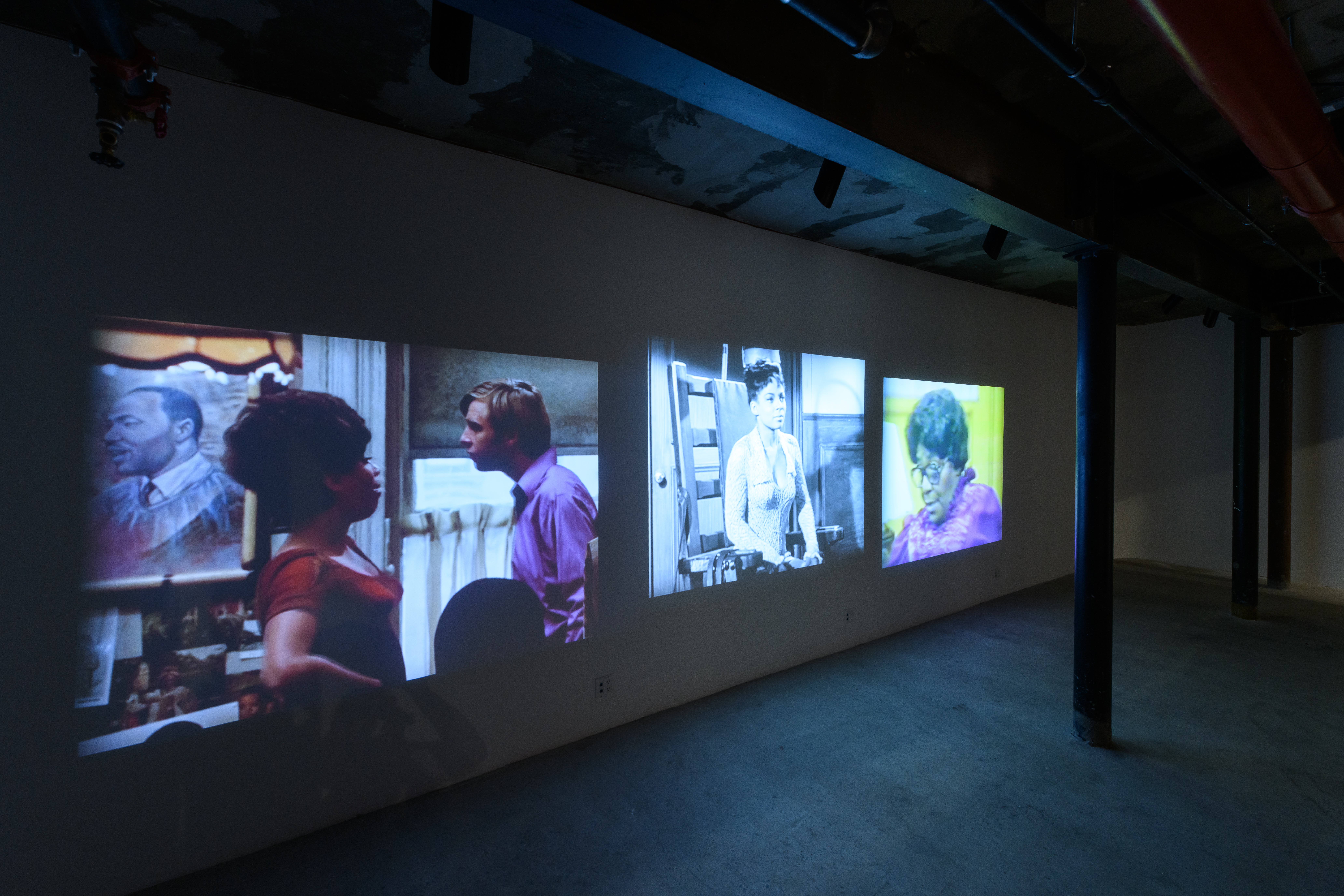 A close up of a series of old Hollywood films projected on the back wall of the exhibition space
