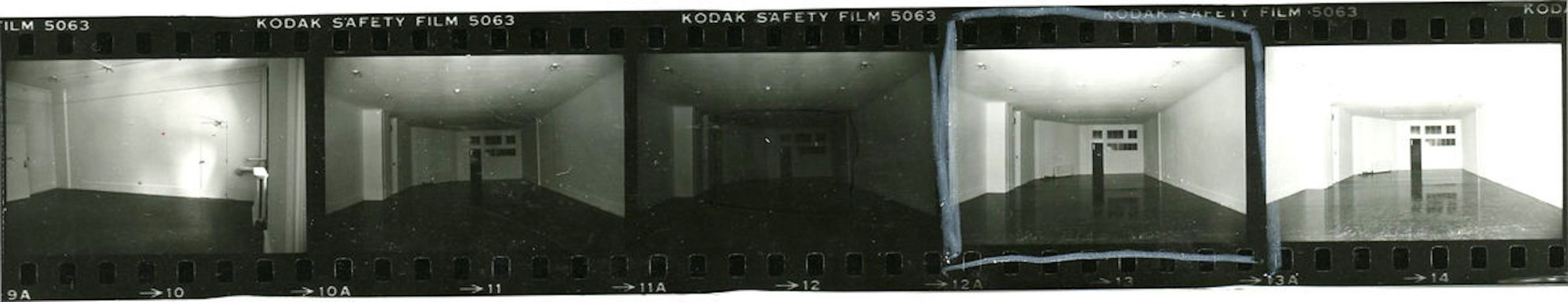 A strip of black and white film negatives of a cavernous gallery space.