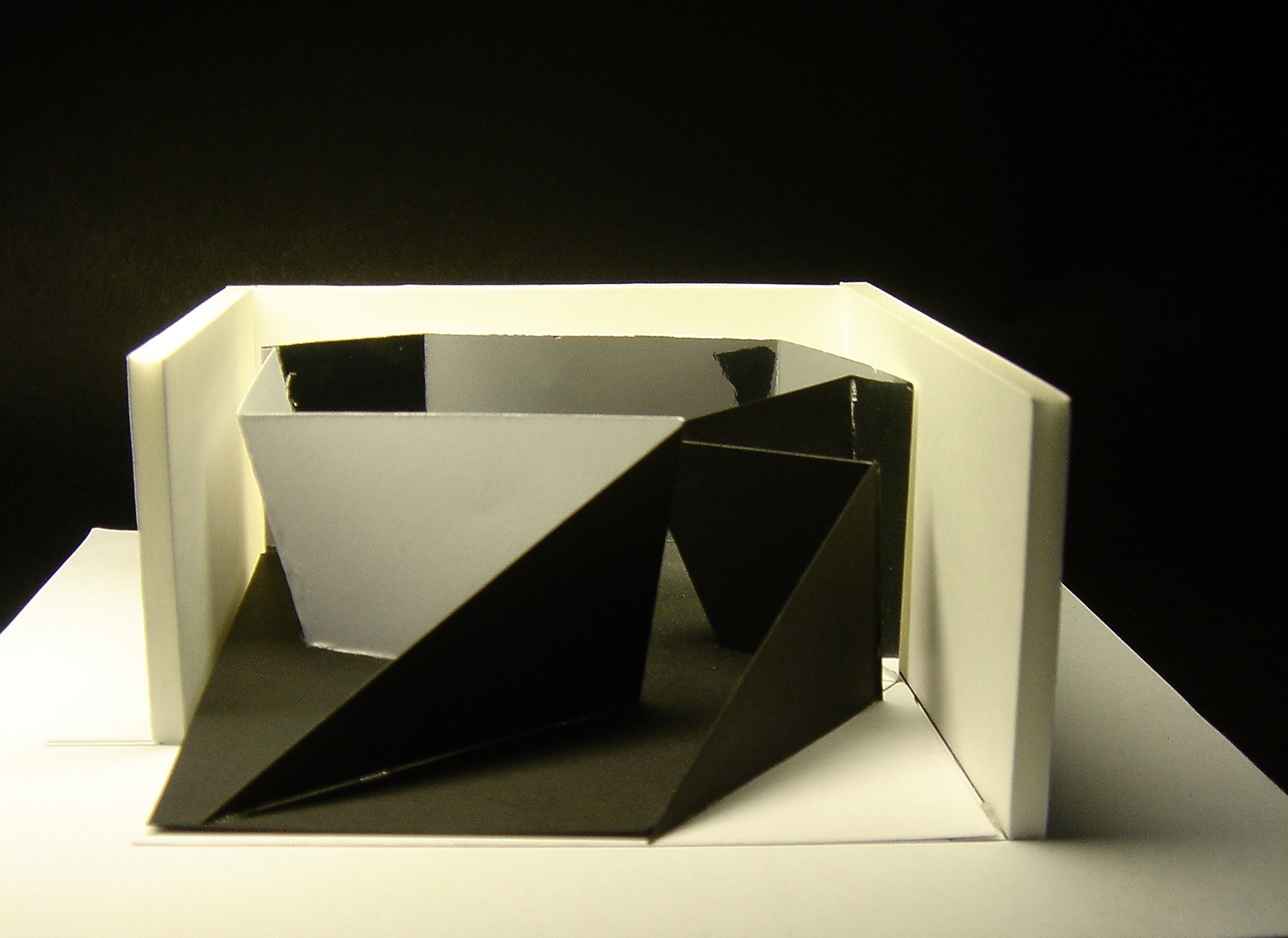 A model of a geometric, folded object with one mirrored side within an open white rectangle.