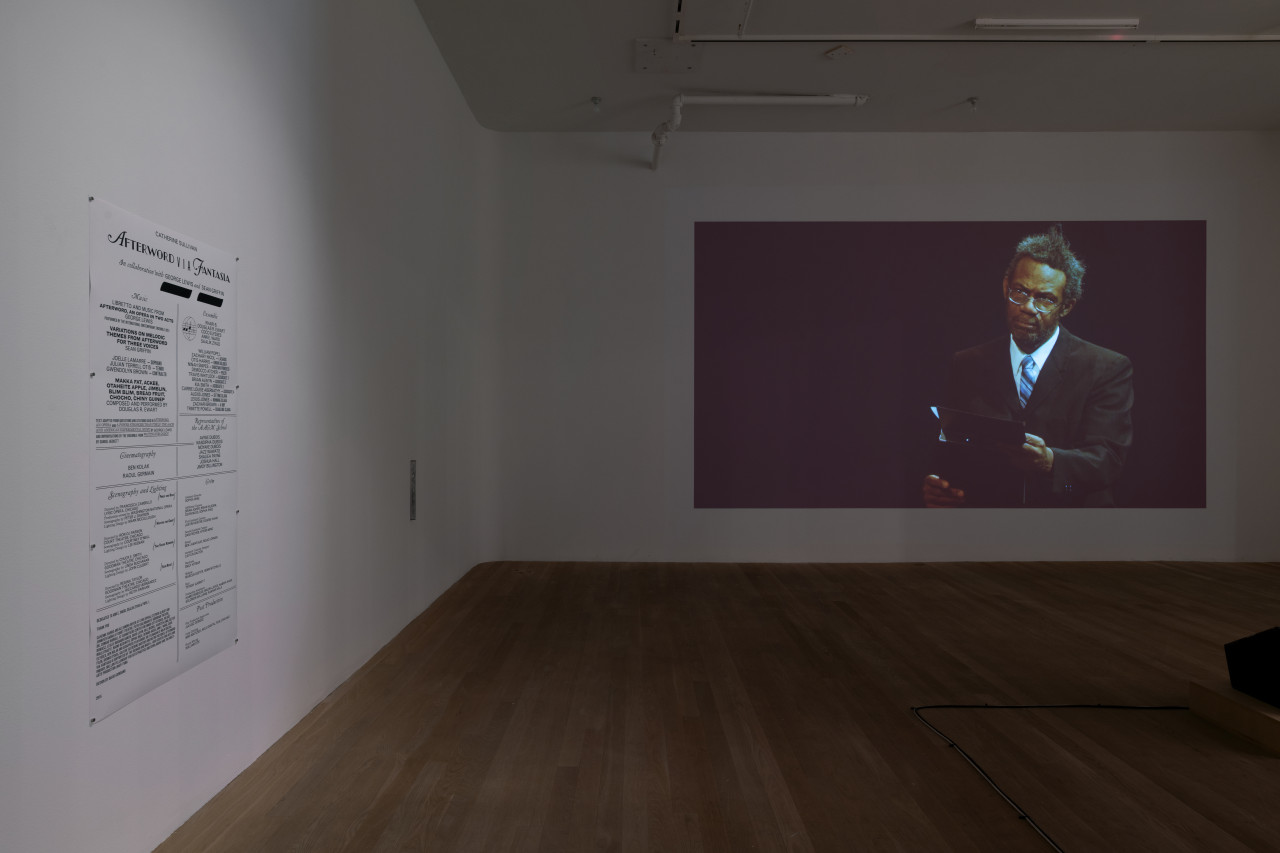 On the left gallery wall is a sheet of paper listing the credits of Catherine Sullivan