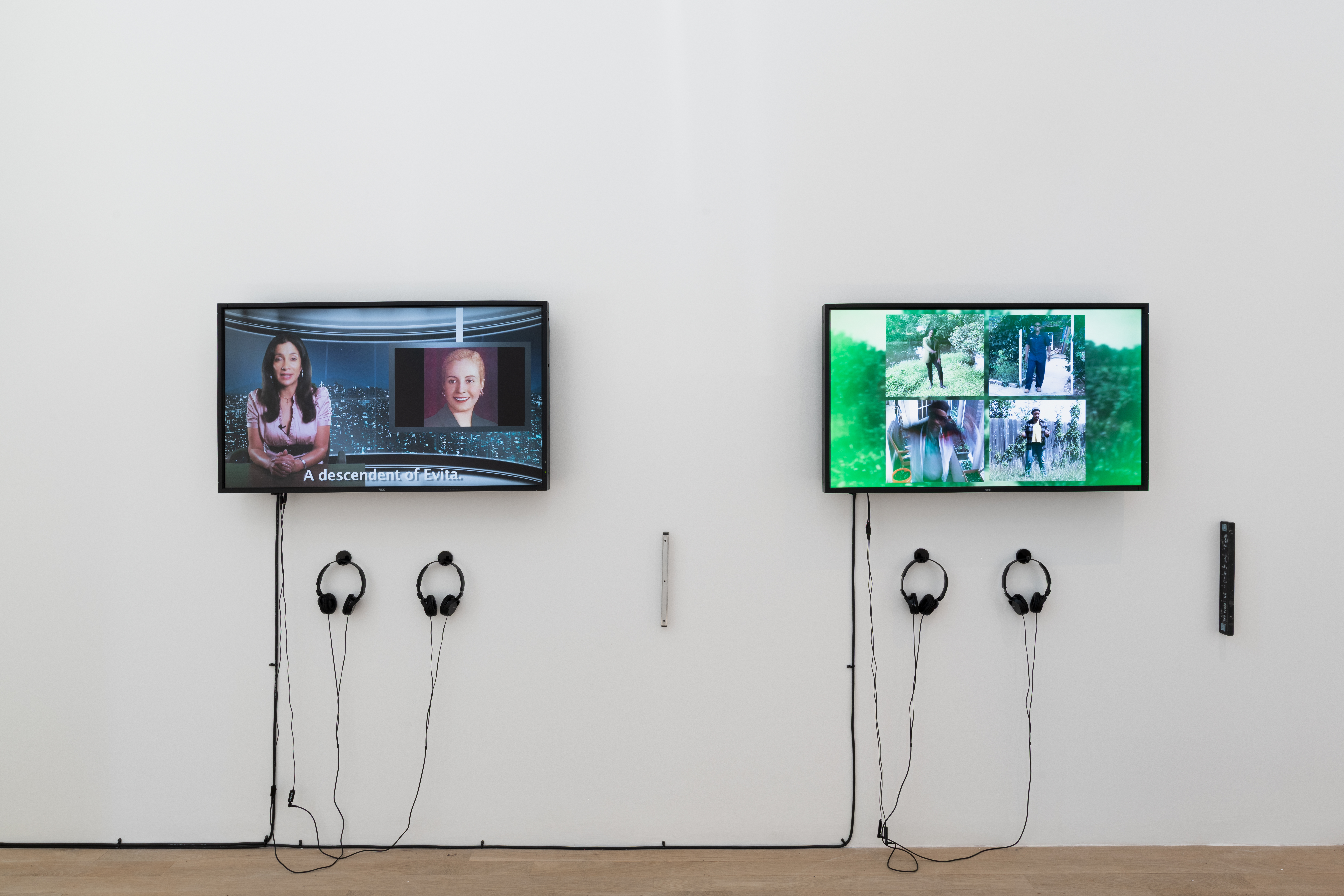 Two televisons sit on the wall, bisected with hung grocery dividers. The television on the left displays a video of a news anchor with the bottom text 