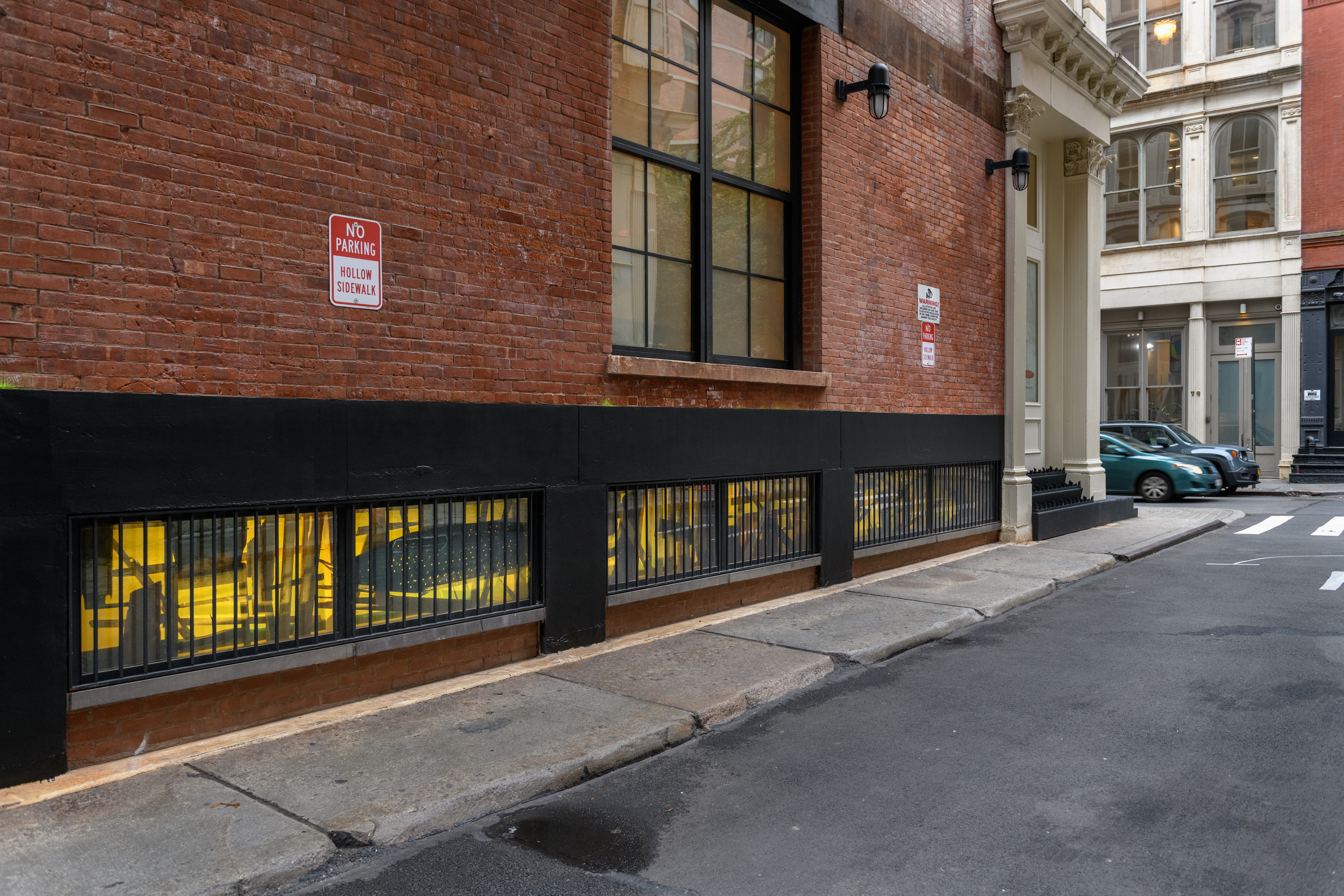 A view of low windows on a brick facade covered in layered black and yellow film.
