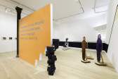 A view of multiple works including an orange wall that reads 