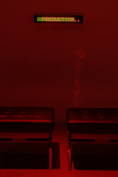 A view of two black leather stools in front of an LED sign crawl of a text.