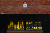A close up of low windows on a brick facade covered in layered black and yellow film.