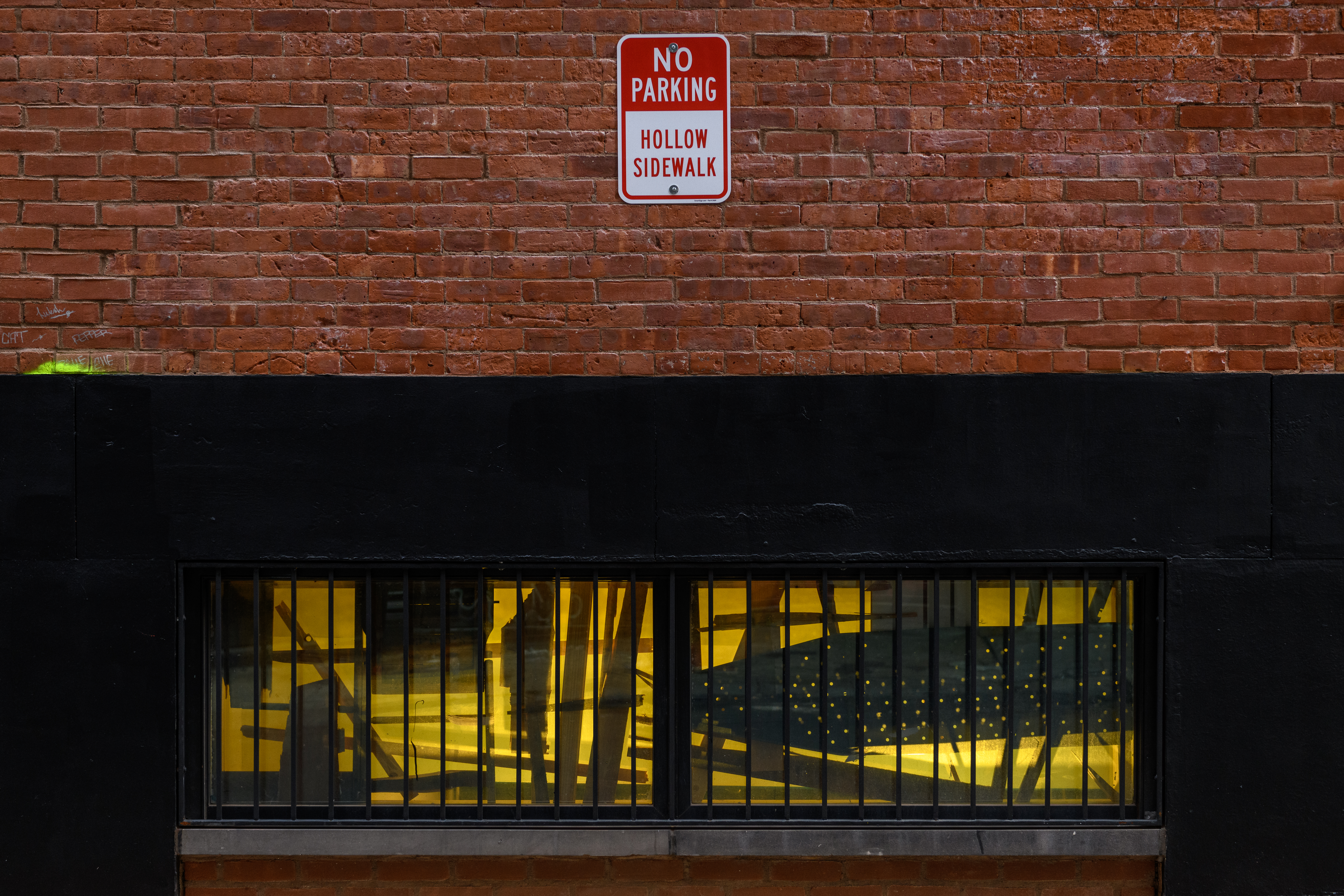 A close up of low windows on a brick facade covered in layered black and yellow film.