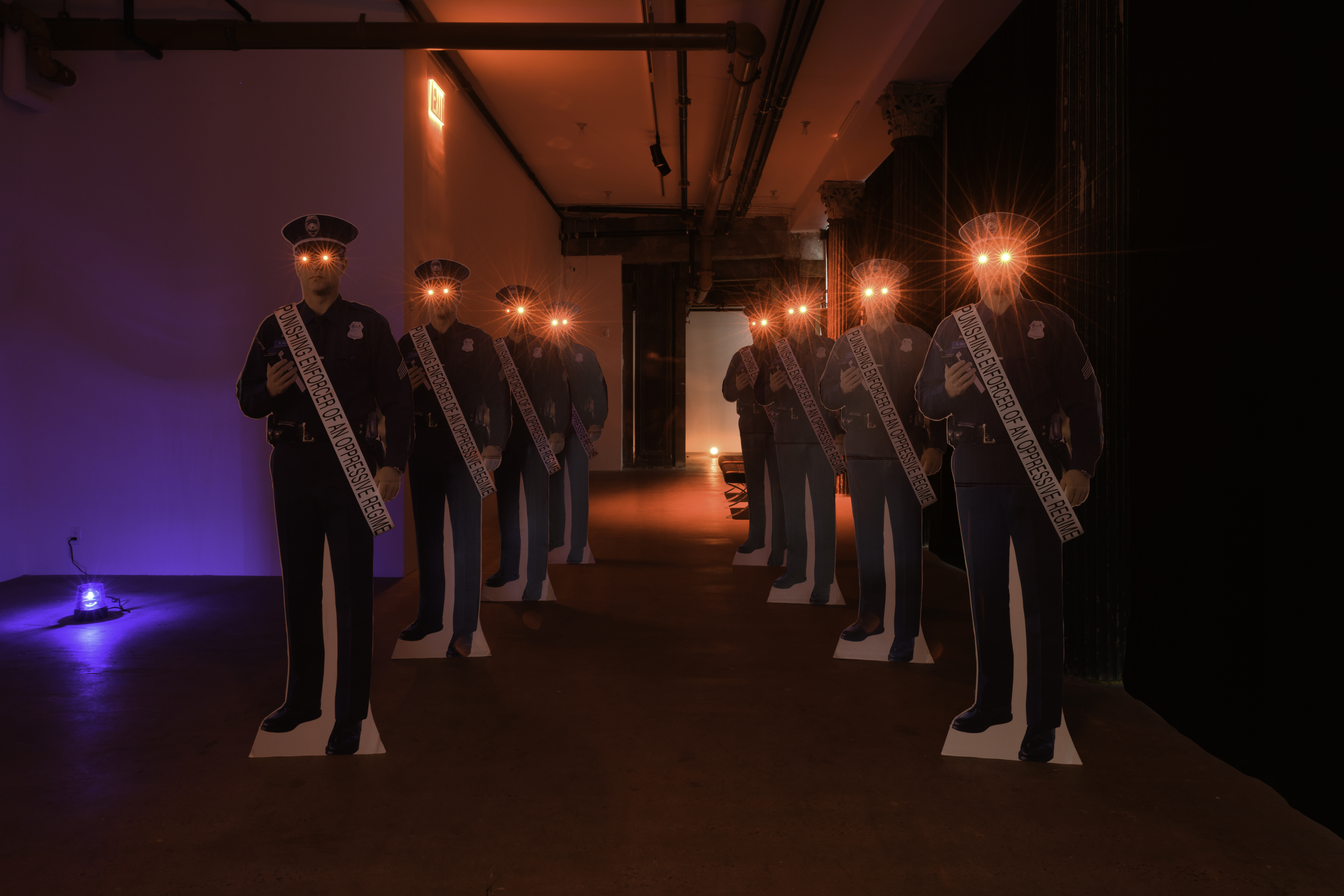 A view of two rows of red-eyed, cardboard cutout, police officers with sashes that read 