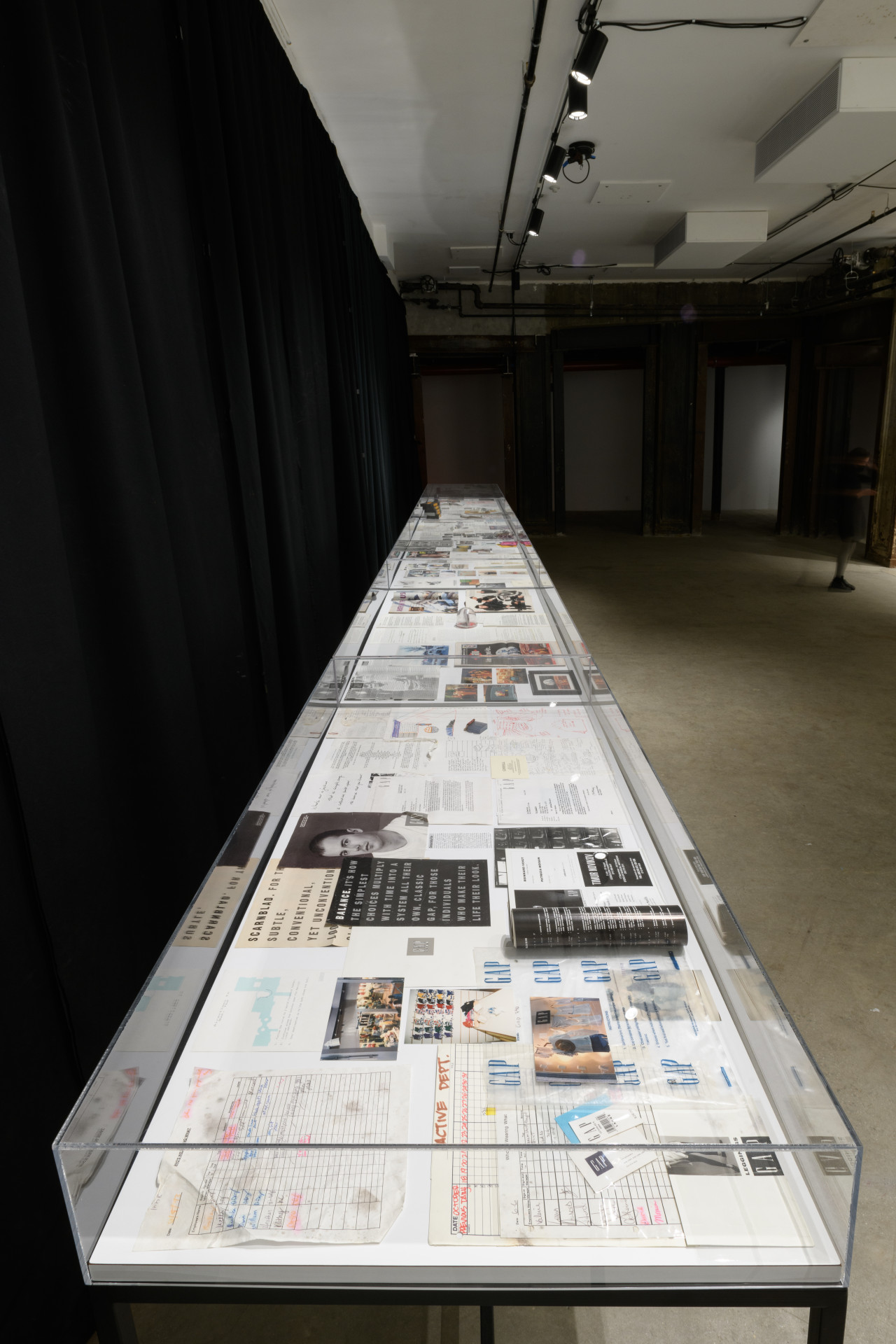 A view of multiple glass cases displaying archival images and documents.