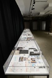 A view of multiple glass cases displaying archival images and documents.