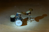 A close up of a dramatically lit small drum kit that reads 