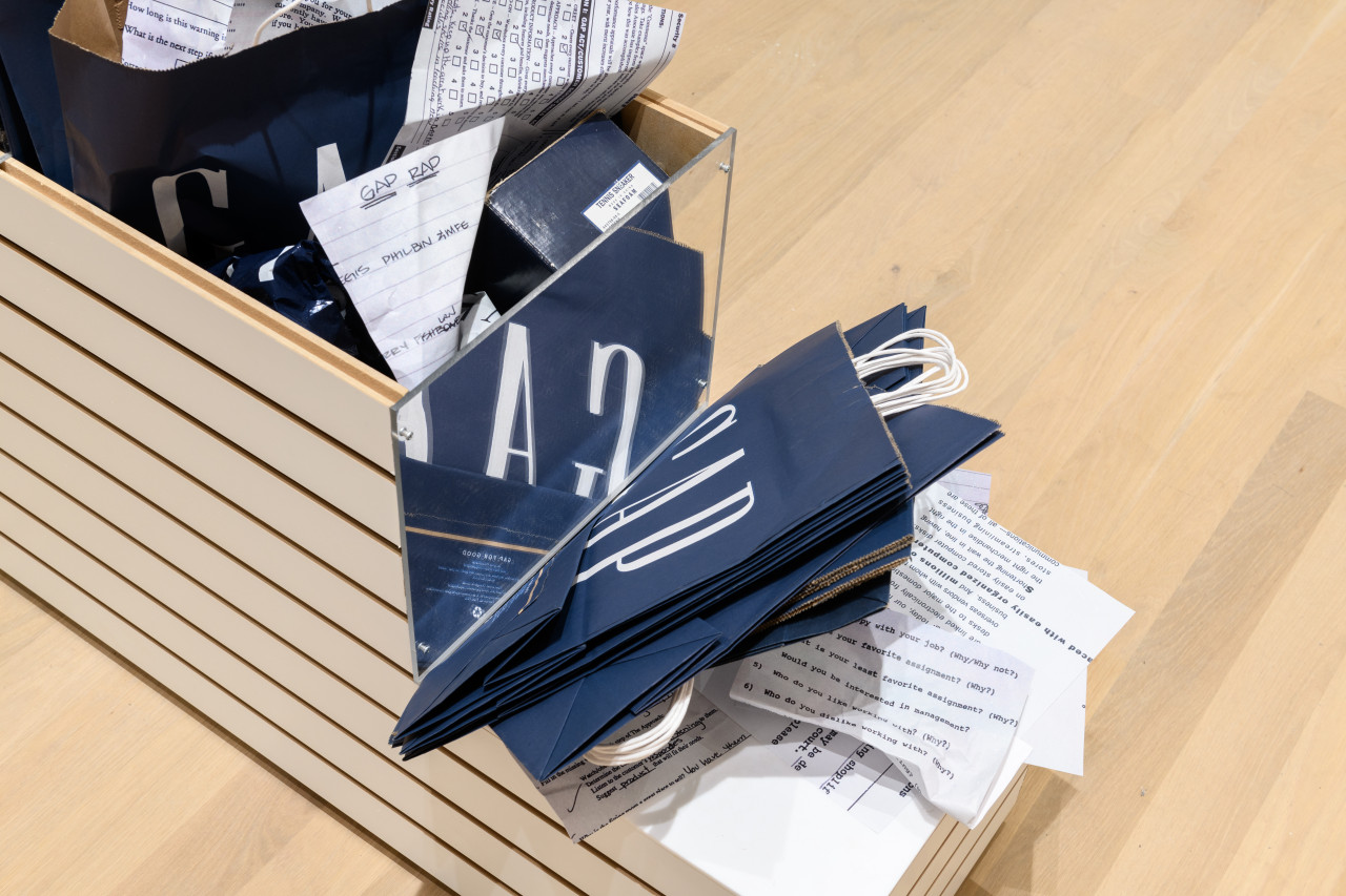 A close up of a store display planter stuffed with Gap clothing store bags and crumpled documents.