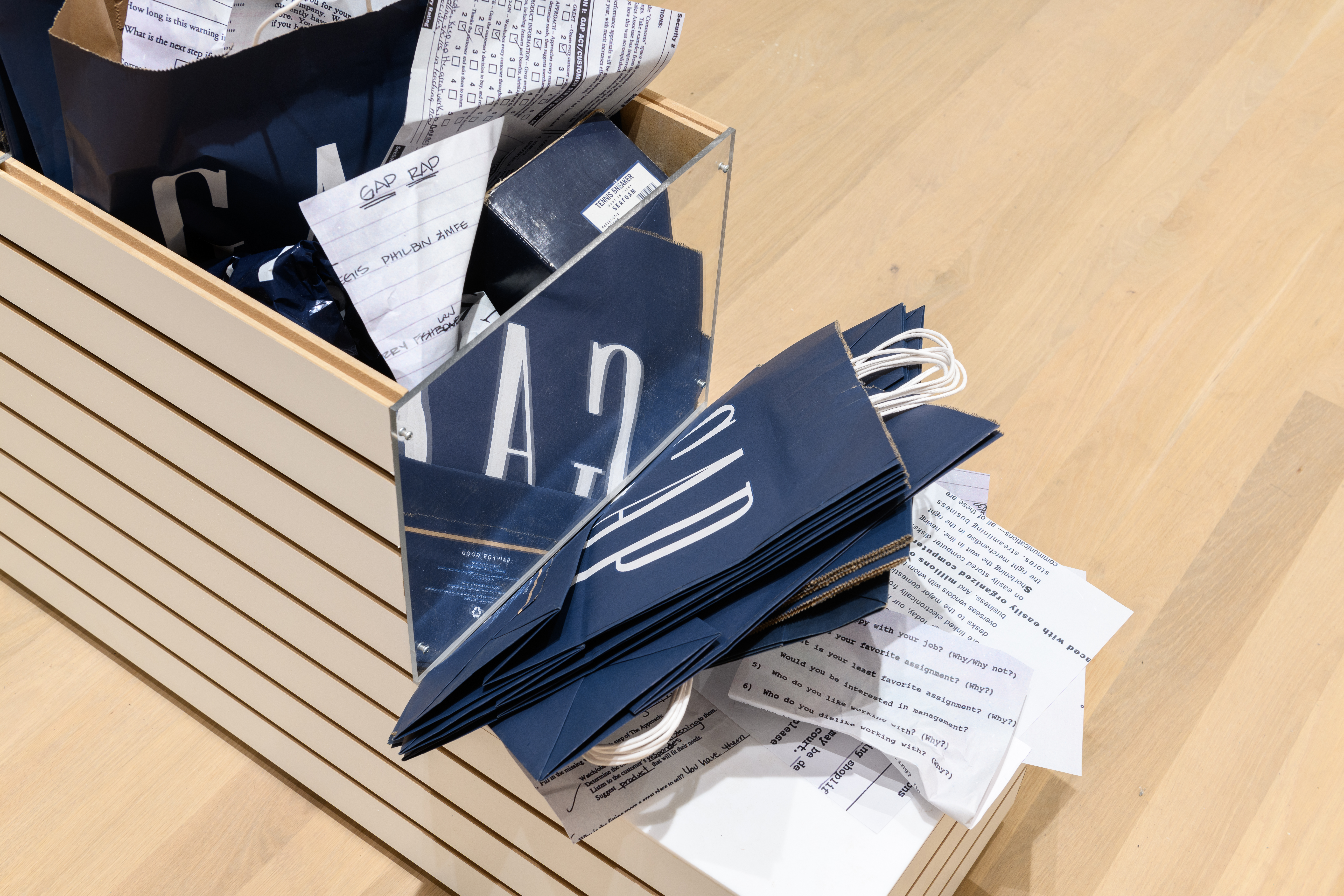 A close up of a store display planter stuffed with Gap clothing store bags and crumpled documents.