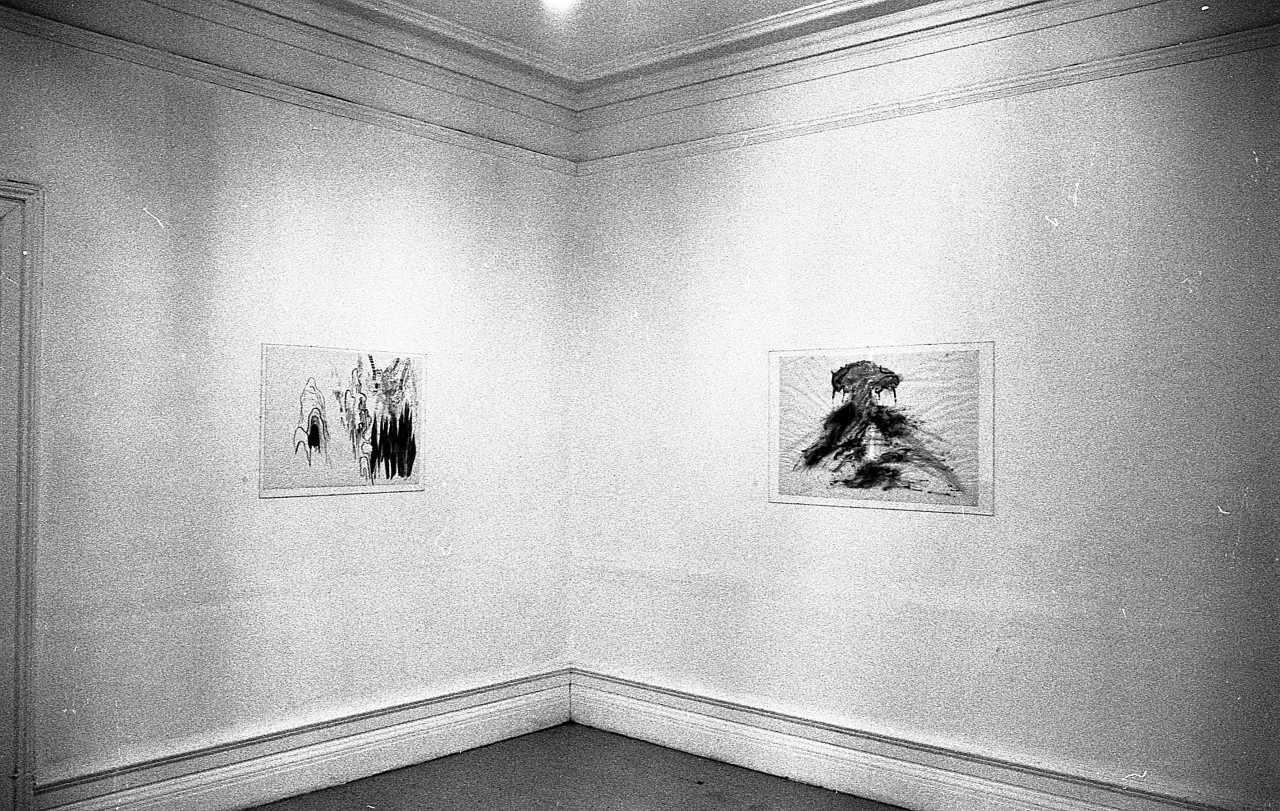 Two drawings are hung up on adjacent walls.