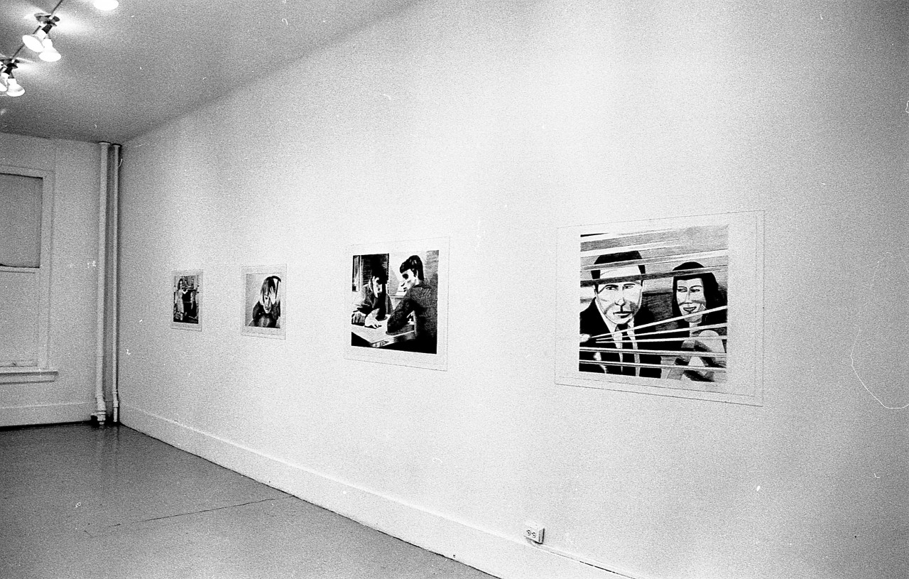 Four drawings are hung in a row on a white wall. The foremost depicts a man and a woman looking out a window through window blinds. The next depicts two men sitting at a table.