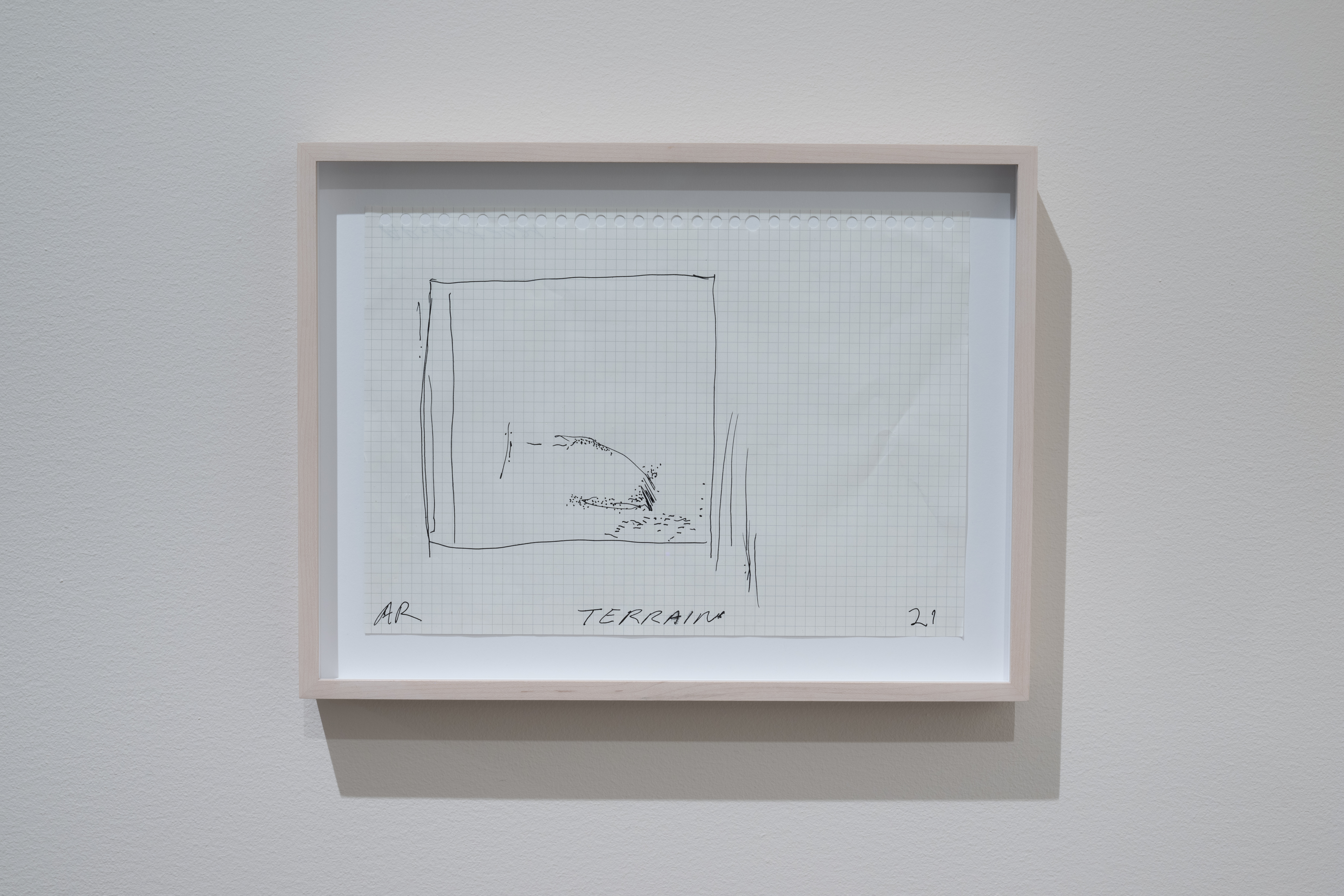 Color image of a framed piece of notebook graph paper, with a pen and ink drawing of a rectangle with various lines and dots. In the bottom-center of the paper is the word 