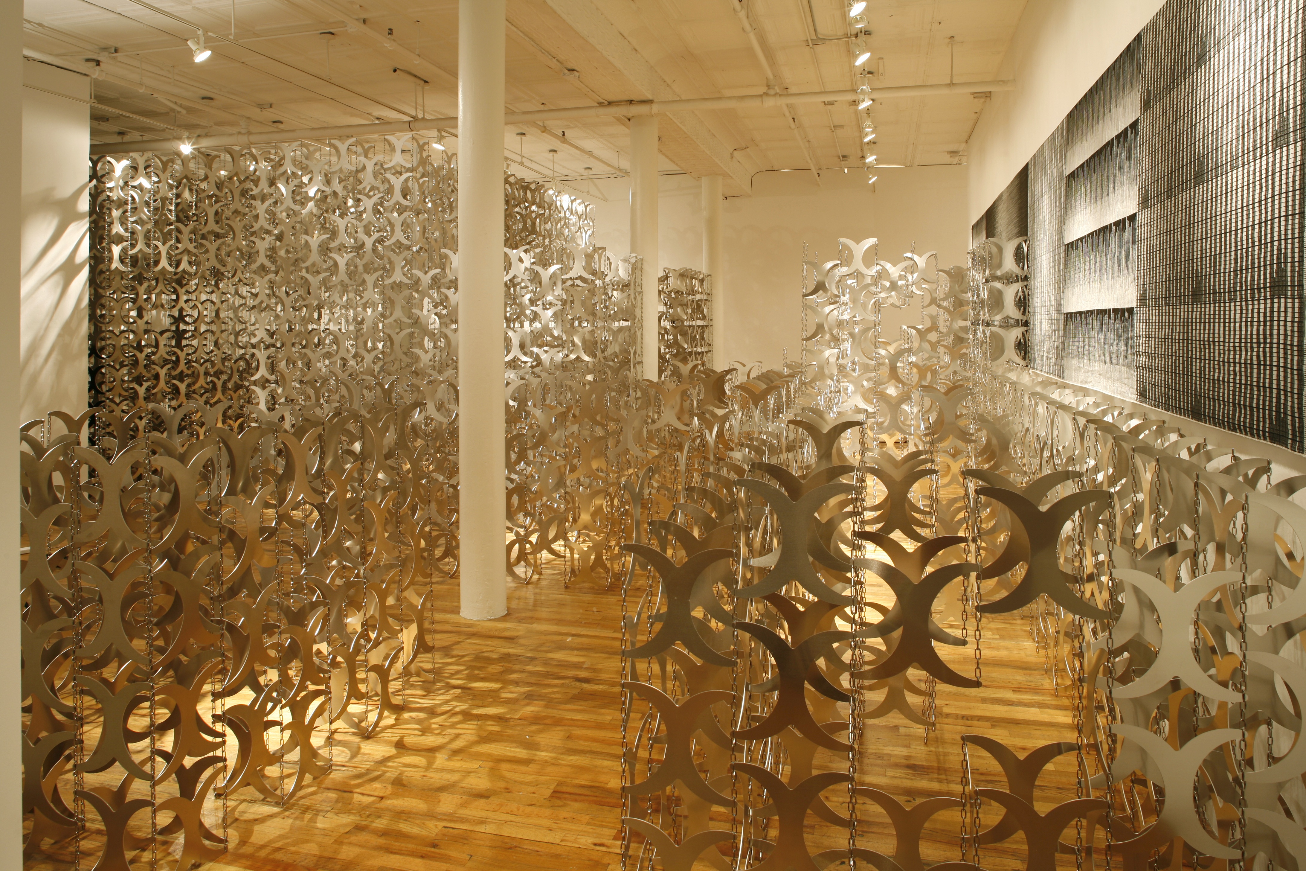 A large gallery space full of hundreds of metal cutouts shaped like curved 