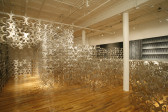 A large gallery space full of hundreds of metal cutouts shaped like curved 