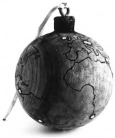A wooden ornament with a string attached at its top, is carved with the outlines of the worlds continents, becoming a miniature globe.