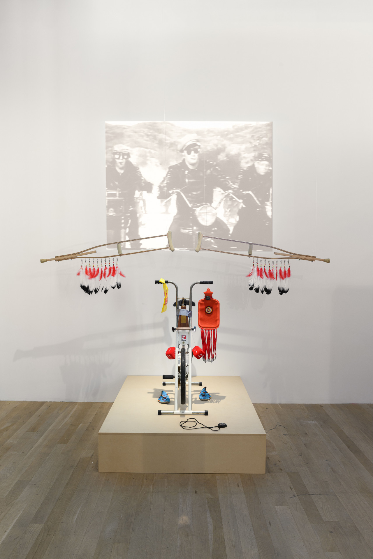 An image of a sculpture made out of bicycle parts, as well as other materials. Behind the sculpture is a projection.