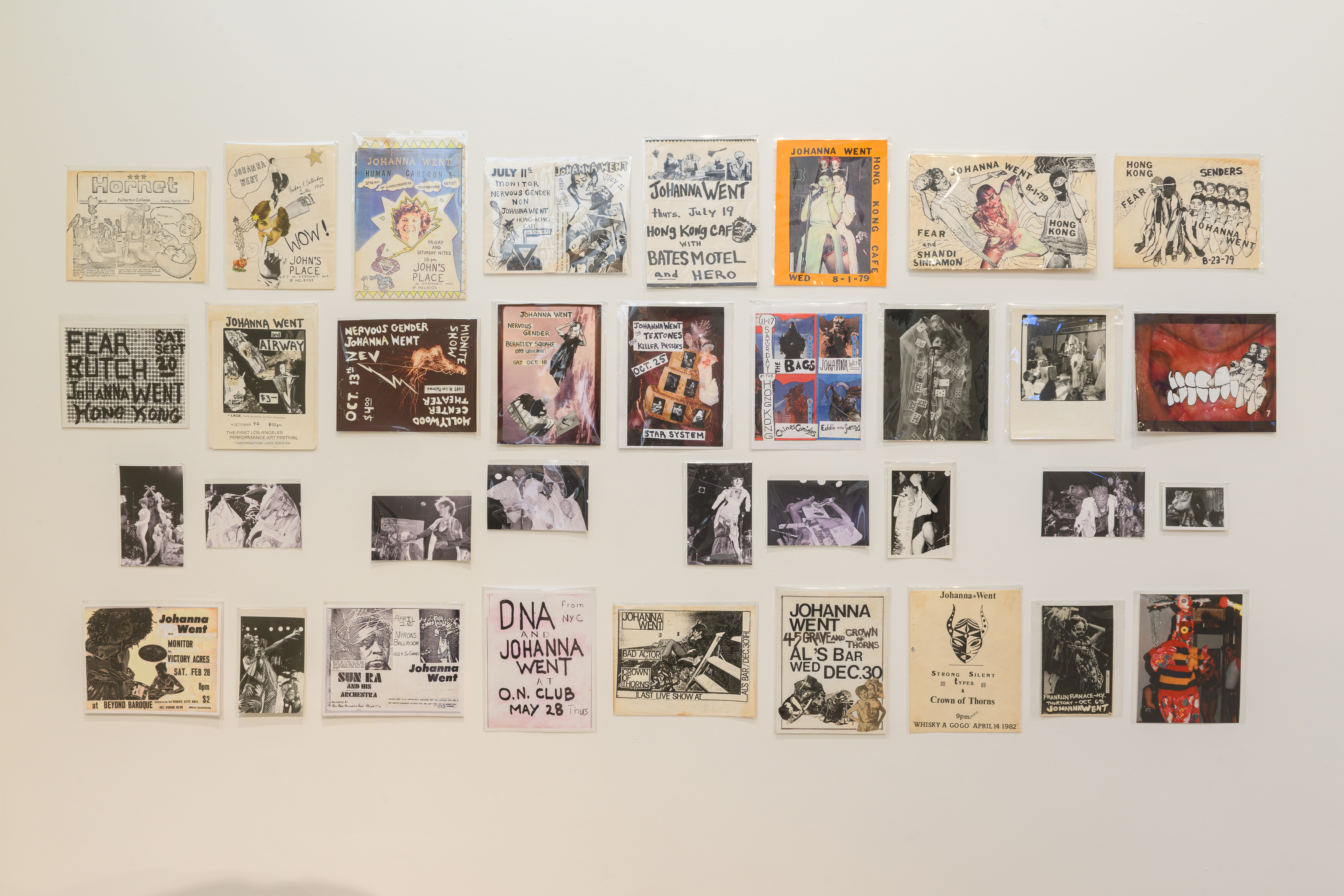 A wall that has various posters, photographs, and collages hanging from it.