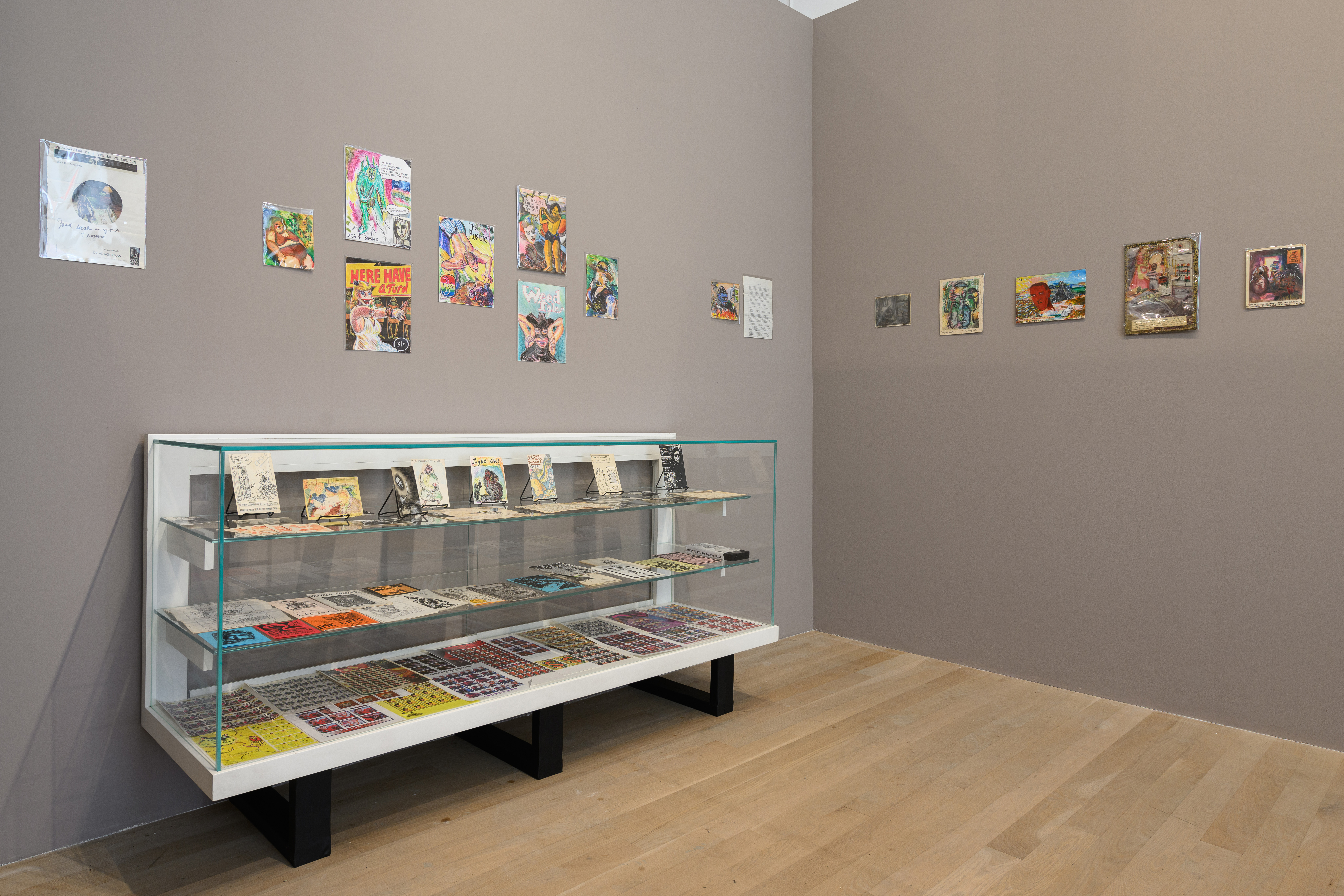 Against the left hand wall is a glass display case, above which and above on the right hang various ephemera.