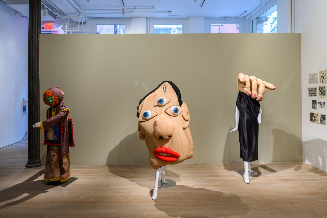 A brightly lit photograph of three human-sized costumes in front of a wall.
