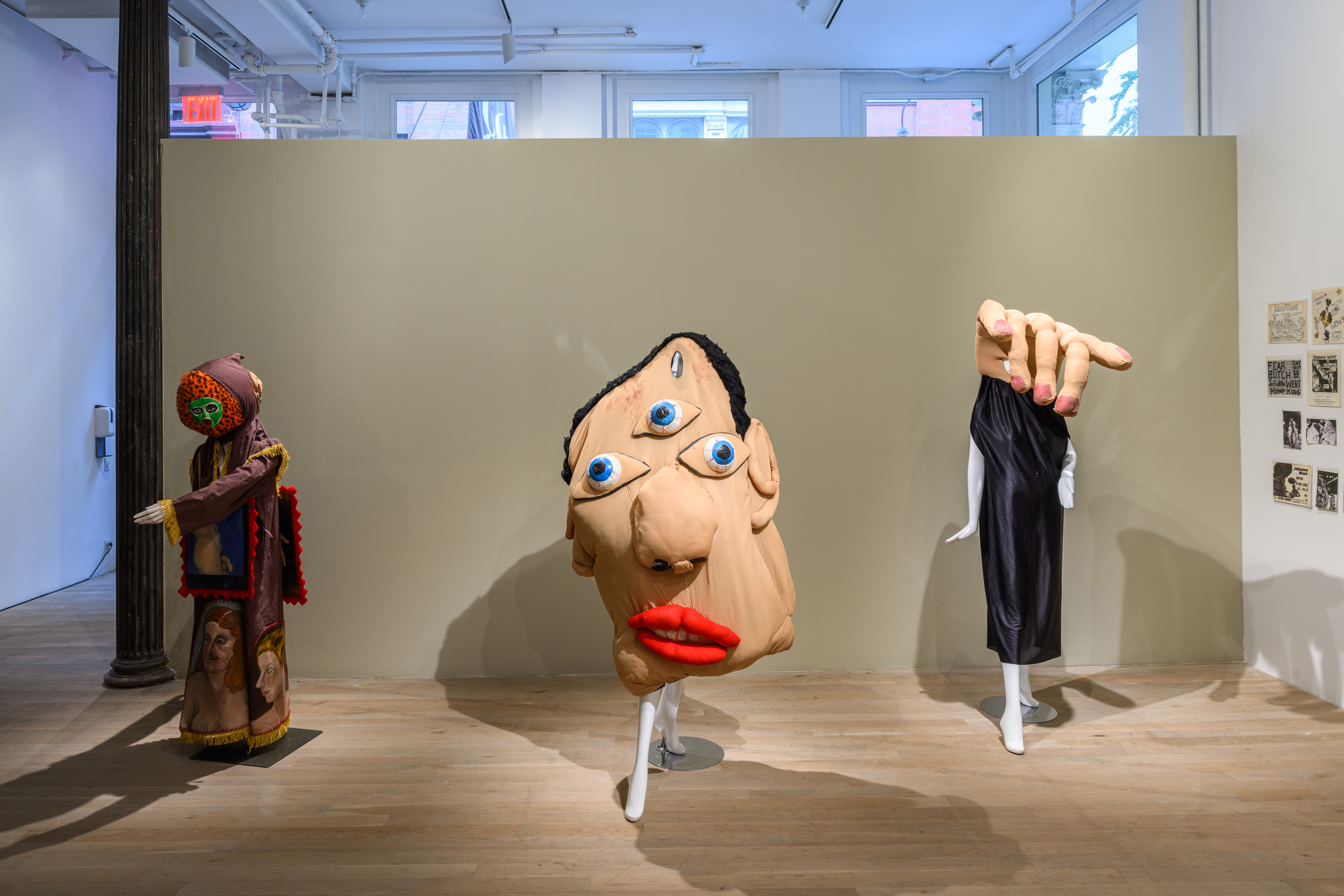 A brightly lit photograph of three human-sized costumes in front of a wall.