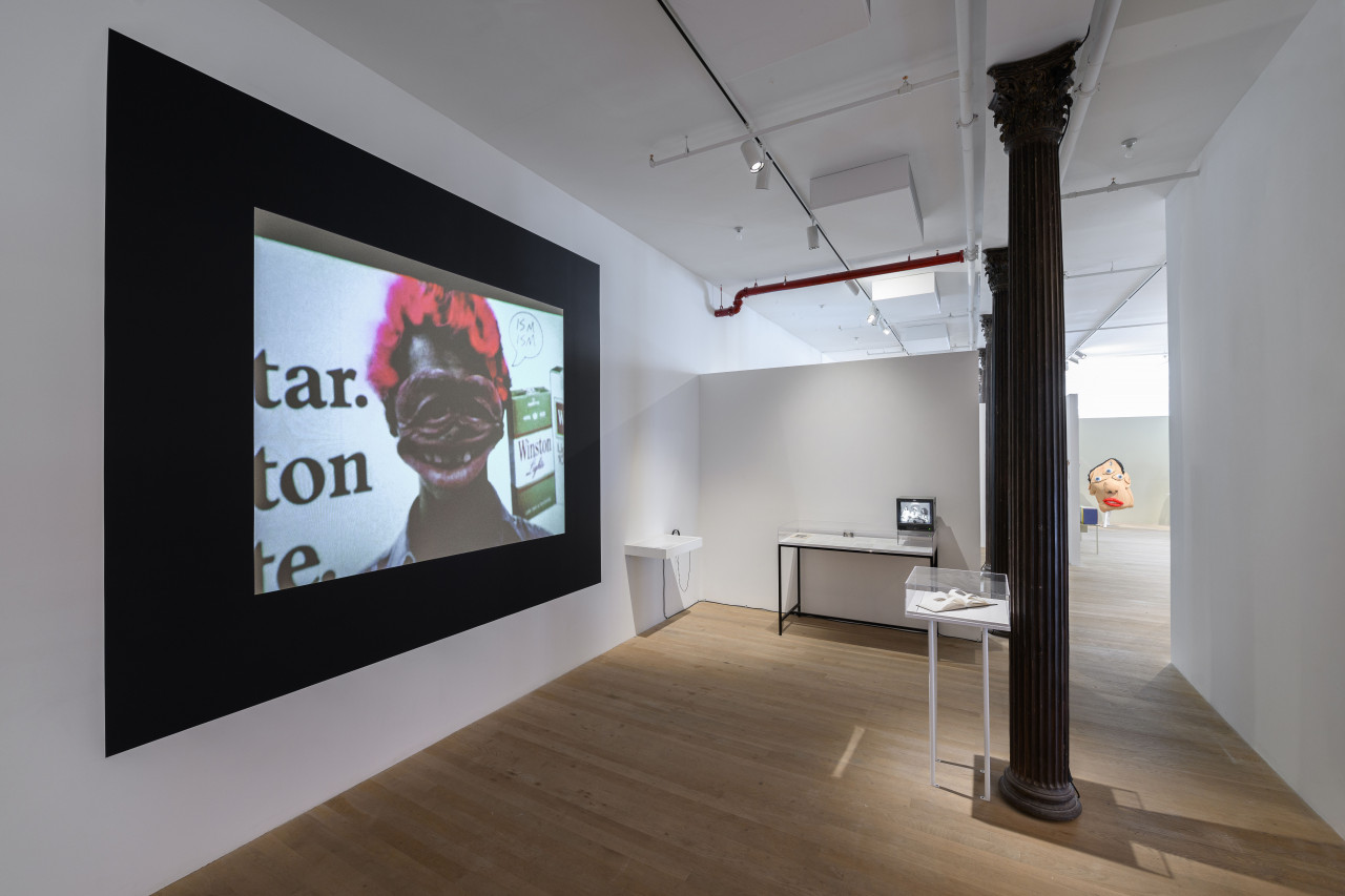 An image of a room with several display cases and a projection, with bright lights cast against the wall.