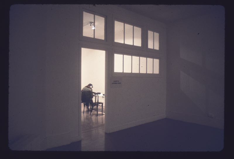 A viewer is visible through the open door to a gallery room.