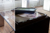 Detail view of a display case with two screens, one resting partially on another. A person's smiling face is visible on the bottom monitor.