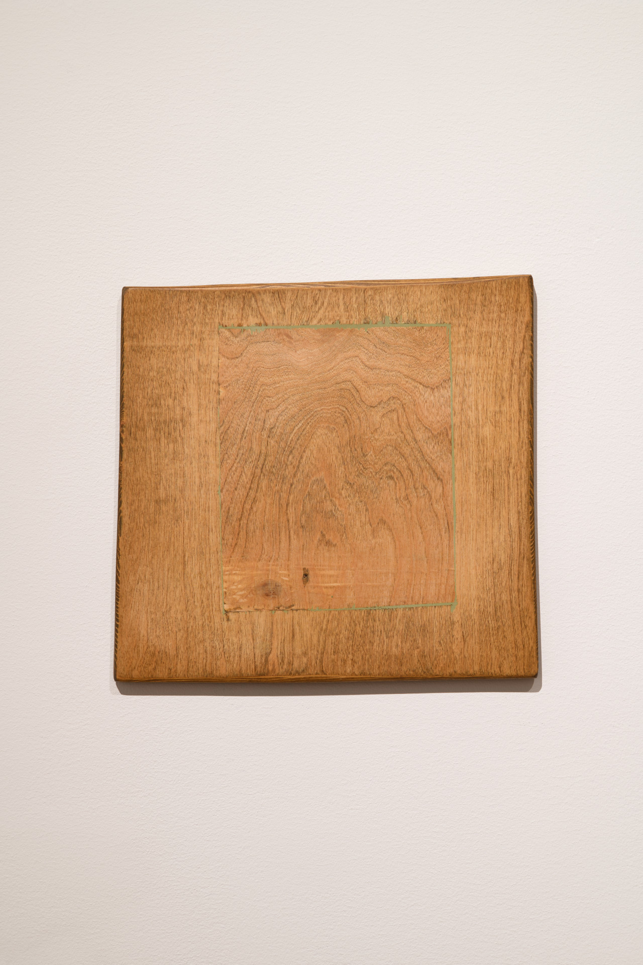 A smaller wooden panel has been inserted into a larger surrounding wooden square. The woods