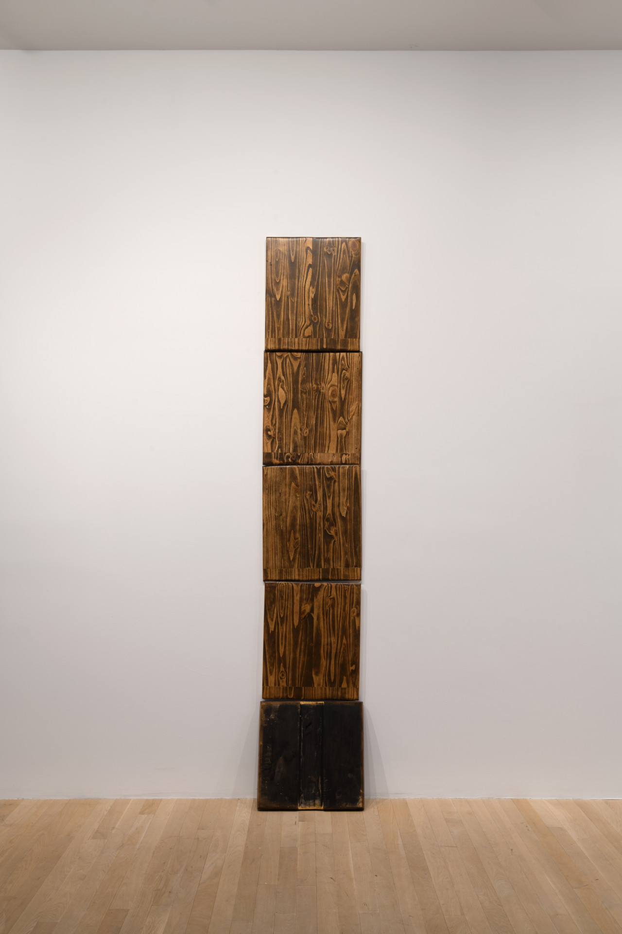 Five wooden panels stack atop one another to vertically scale the wall.