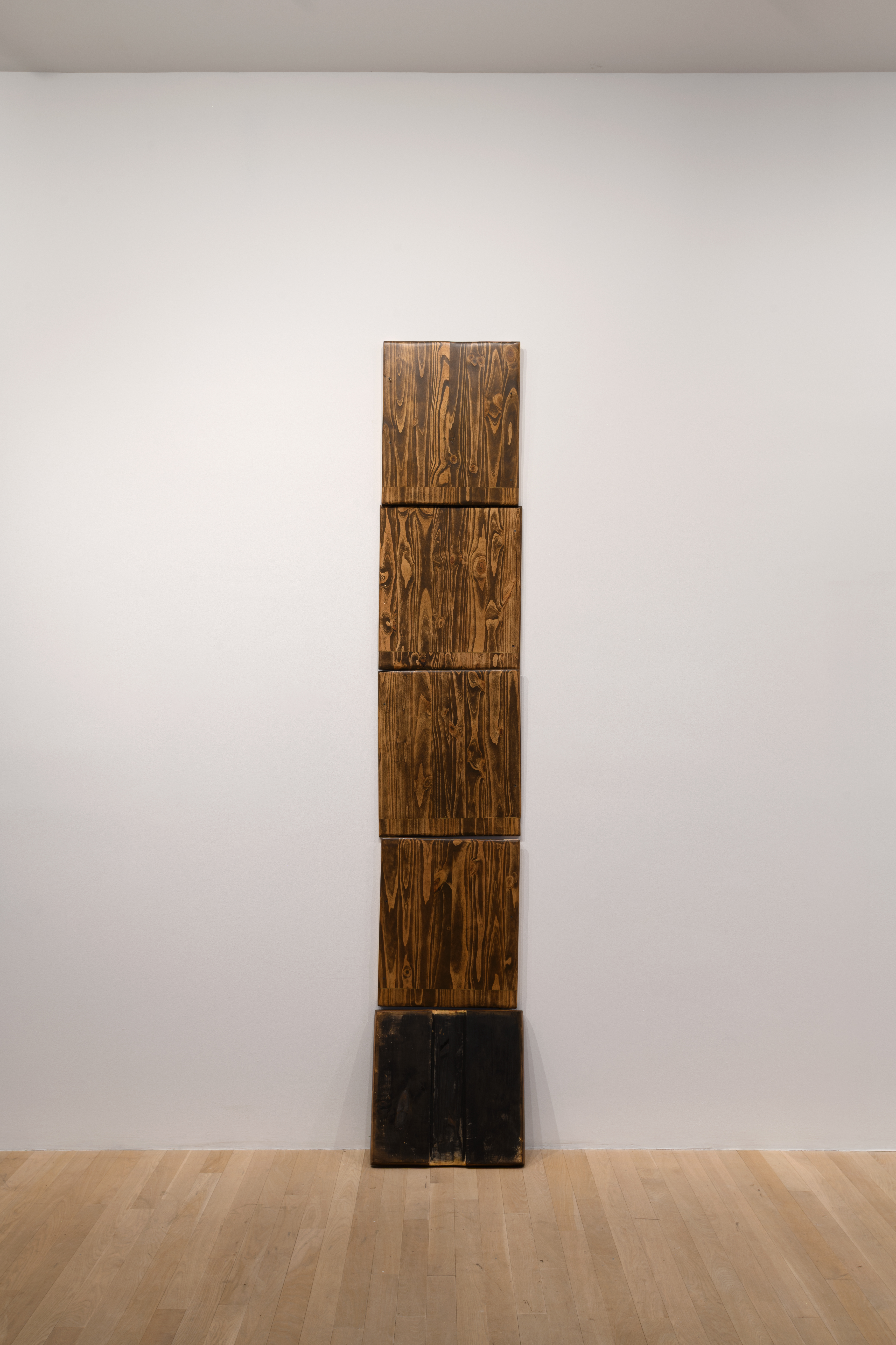 Five wooden panels stack atop one another to vertically scale the wall.