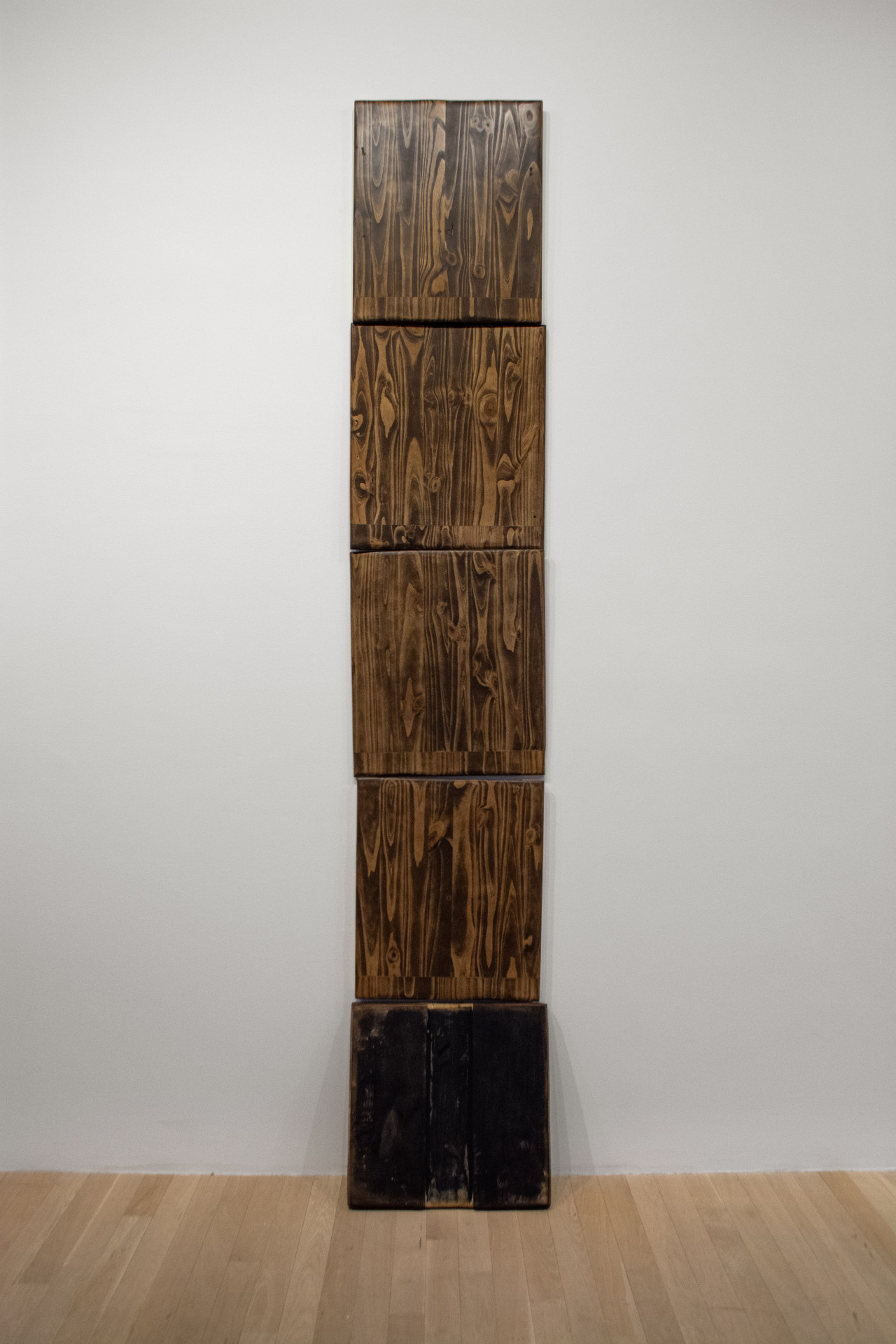 Five wooden panels stack atop one another to vertically scale the wall.