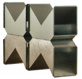 A geometric metal sculpture against a blank, white background. The sculpture is composed of four identical components, each with two triangular spikes extending upwards or downwards. Each of the components is hollow, and the interior of the sculpture can be glimpsed from its side.